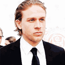 a man in a suit and tie stands in front of a sign that says lc