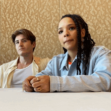 a man and a woman are sitting at a table and the woman has a ring on her finger