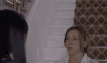 two women are standing next to each other in front of a staircase .