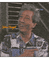 a man in a colorful shirt is smiling and pointing at the camera