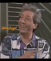 a man in a colorful shirt is smiling and pointing at the camera