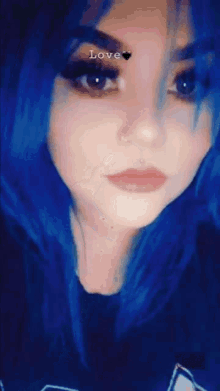 a woman with blue hair is pointing to her face with the word love above her