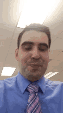 a man wearing a blue shirt and a pink and blue tie