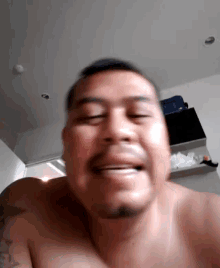 a shirtless man with a tattoo on his arm is smiling with his eyes closed