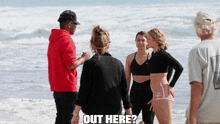 a group of people standing on a beach with out here written below them