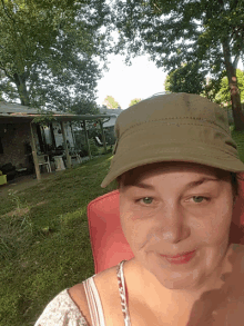 a woman wearing a hat is sitting in a chair in front of a house