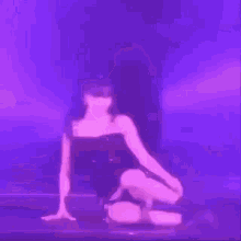 a woman is dancing on a stage in front of a purple background .
