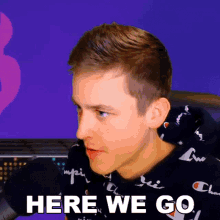 a man wearing a black champion sweatshirt says here we go
