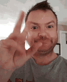 a man with a beard is making a peace sign with his hand