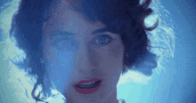 a close up of a woman with blue eyes and red lips