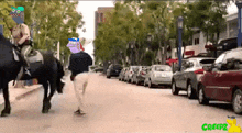 a man riding a horse down a street with a creepz logo on the bottom right