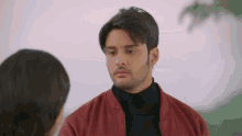 a man in a red jacket looks at a woman
