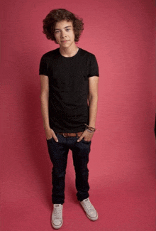 a young man wearing a black t-shirt and white converse shoes