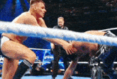 two men are wrestling in a ring while a referee watches .