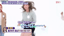a girl in a gray sweater is dancing in front of a screen that says statv on it