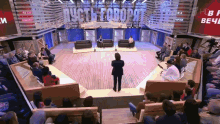 a woman stands on a stage in front of a crowd with a sign that says " пусть говорят " behind her