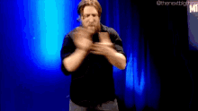 a man in a black shirt is dancing on a stage in front of a blue light .