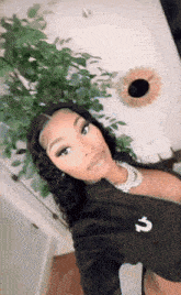 a woman is taking a selfie in front of a plant and a mirror