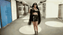 a woman with long hair is walking down a hallway in a building .