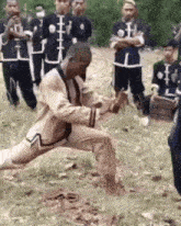 a group of men are standing in a field and one of them is kneeling down in the grass .