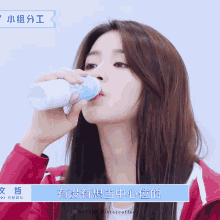 a woman drinking from a bottle with chinese writing on the bottom