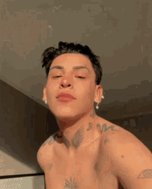 a shirtless young man with a lot of tattoos on his chest and neck