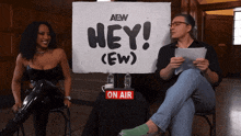 two people sitting in front of a sign that says hey ew