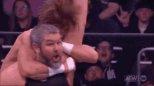 a man with a beard is being punched in the face by a wrestler in a ring .