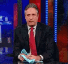 a man in a suit and tie is holding a tissue in his hand