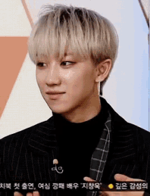 a young man with blonde hair is wearing a black jacket and a black turtleneck sweater .