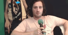 a man is wearing headphones and holding a microphone in front of a green screen .