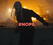 a woman is standing in front of a fire with #nope written on her back
