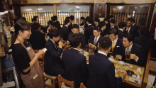 a group of men in suits are sitting around a table eating and drinking