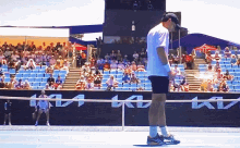 a man stands on a tennis court in front of a ktm advertisement