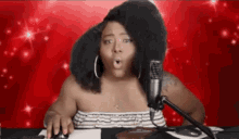 a woman with a large afro is sitting in front of a microphone and a mouse .