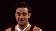 a man wearing a tie and a tank top is smiling .