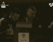 a man covering his face in front of a sign that says press box row b.