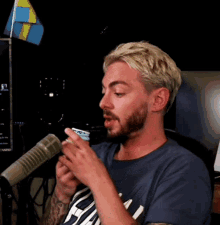 a man with a beard is holding a cup in front of a microphone