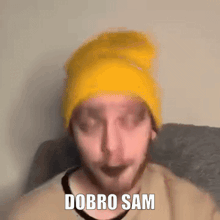 a man wearing a yellow beanie says " dobro sam " in front of his face