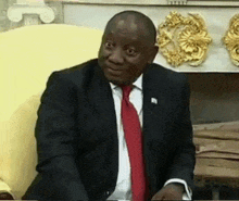 a man in a suit and tie is sitting in a chair and smiling .