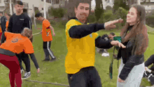 a man in a yellow shirt is dancing with a girl in an orange shirt .