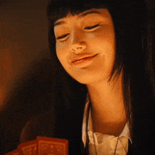 a young woman with long black hair is smiling while holding a tarot card .