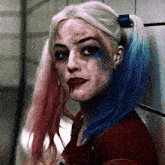 a close up of harley quinn 's face with blue and red hair