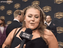 a woman holding a microphone that says instinct culture on it