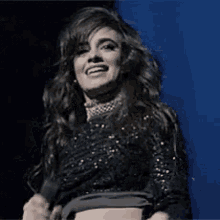 a woman in a crop top is dancing on a stage with her arms in the air .
