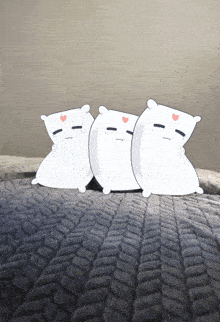 three white pillows with hearts on their faces are sitting on a blanket