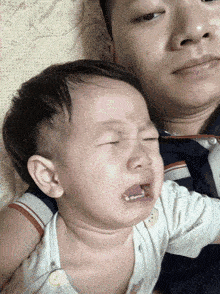 a baby is crying while being held by a man on a bed