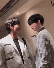 two men in suits are standing next to each other and looking at each other ..