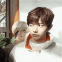 a young man is making a funny face while standing next to another man .