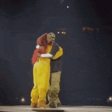 two people hugging on a stage in front of a sign that says ' tc ' on it